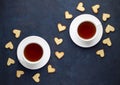 Cups of tea and shaped heart cookies on stone background.