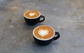 Cups of two hot cappucino are the concrete background. Heart shape art latte symbol of love Royalty Free Stock Photo