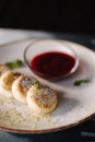 Curd fritters decorated powdered sugar in plate. Cheesecake, fresh jam, sour cream and mint.