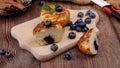 Curd muffins with blueberry filling, one of which is cut in half, and fresh blueberries on a chopping board on a table Royalty Free Stock Photo