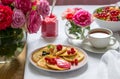 Curd pancakes with berry curd served with tea on a table decorated with bouquets of roses Royalty Free Stock Photo