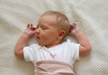 Newborn baby girl wearing white bodysuit lying on the bed Royalty Free Stock Photo