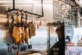 Cured Hams Hanging in a Spanish Delicatessen. Traditional Spanish cured hams hang above a display of knives, in a