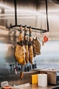 Cured Hams Hanging in a Spanish Delicatessen. Traditional Spanish cured hams hang above a display of knives, in a