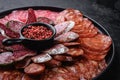 Cured meat platter of traditional spanish tapas. Chorizo, salchichon, longaniza and fuet on black textured background