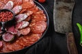 Cured meat platter of traditional spanish tapas. Chorizo, salchichon, longaniza and fuet on black textured background