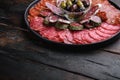Cured meat platter of traditional spanish tapas. Chorizo, salchichon, longaniza and fuet on dark wooden background with space for