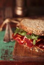 Cured meat sandwich with seeded bread on old wooden table