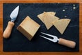 Cured sheep cheese. Cut into pieces on wooden board and black slate. Fork and knife for cheese. Top View Royalty Free Stock Photo