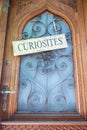 Curiosities sign hanging on wooden door with blue glass window and metal door handle Royalty Free Stock Photo