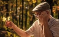 Curiosity to botany. Explore world around. Pensioner hiking in forest on sunny autumn day. Old man collect leaves