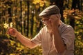 Curiosity to botany. Explore world around. Pensioner hiking in forest on sunny autumn day. Old man collect leaves Royalty Free Stock Photo