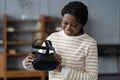 Curious afro lady holding futuristic innovative VR glasses, testing virtual reality headset at first