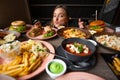 Curious anticipant woman blogger with lips in tube looking at abundance of snack tasty, delicious food for mukbang video