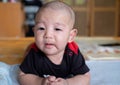 Curious Asian infant baby boy lie on the stomach or prone, wearing black red clothes on the bed