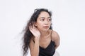 A curious asian woman wanting to listen on the latest gossip.Leaning forward to hear better. Isolated on a white background