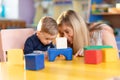 Curious baby and kindergartener playing developmental toys