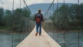 Curious backpacker traveling nature in mountains. Tourist walk on river bridge. Royalty Free Stock Photo