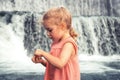 Curious beautiful child girl toddler portrait playing at waterfall during summer vacation concept happy childhood lifestyle