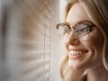 Curious blond girl enjoying view from window louvers