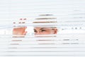 Curious blonde woman looking through venetian blind