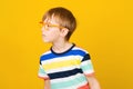 Curious boy looking aside and listens somethink. Smart boy in glasses over yellow background