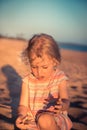 Curious child girl toddler portrait playing on beach with hermit crab during summer vacation concept childhood lifestyle