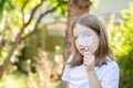 Curious clever elementary school age child, girl looking at the camera through a magnifying glass, holding a loupe in hand