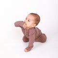 Baby boy in brown clothes crawling and biting own hand Royalty Free Stock Photo