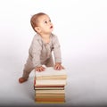 Surprised baby boy in cream clothes playing with books Royalty Free Stock Photo