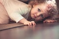 Curious cute child hiding under the bed in kids room and looking scared Royalty Free Stock Photo