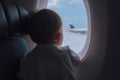 Curious cute little Asian 2 -3 years old toddler baby boy child looking out from airplane window during flight on airplane Royalty Free Stock Photo