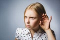 Curious Disappointed girl listens. Closeup portrait child hearing something, parents talk, hand to ear gesture isolated