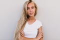 Curious fair-haired lady looking to camera. Indoor photo of fashionable girl in white tank-top