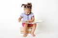 Curious female child with two funny pony tails, sits on pile of