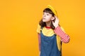 Curious girl teenager in french beret, denim sundress looking aside, eavesdrop with hearing gesture isolated on yellow