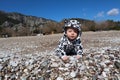 Curious happy little baby child crawling on the pebble beach in Cirali, Turkey under blue sky Royalty Free Stock Photo