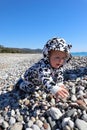 Curious happy little baby child crawling on the pebble beach under blue sky Royalty Free Stock Photo