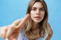 Curious and intrigued woman poking at camera with finger as if checking anyone there looking at her, bending forward