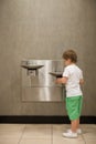 Curious kid boy drinking water from drinking fountain. Stainless Steel drinking fountains mounted at different heights. Young Royalty Free Stock Photo