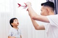 Curious kid looking at the plane toy and playing with father. Asian family playing toys together at home. Royalty Free Stock Photo