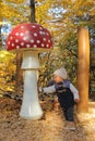 Curious kid playing with giant wooden mushroom Royalty Free Stock Photo