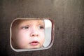 Curious kid spying through the hole in the wooden wall on playground Royalty Free Stock Photo