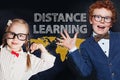 Curious kids and distance education concept. Happy smiling school boy and smart strong girl on blackboard background Royalty Free Stock Photo