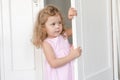 Cute girl peeping out of door in room Royalty Free Stock Photo