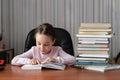 A curious little girl, a child with pleasure, reads a book and takes lessons. Royalty Free Stock Photo