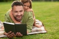 Curious little girl watching her dad reading a book while lying on a blanket. Happy young father and his daughter having Royalty Free Stock Photo