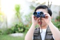 Curious little young Asian boy looking trough a blue binoculars in the garden
