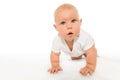 Curious looking baby crawls wearing white bodysuit