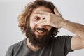 Curious man cannot wait to look what you hiding. Portrait of positive good-looking eastern guy with beard covering eyes